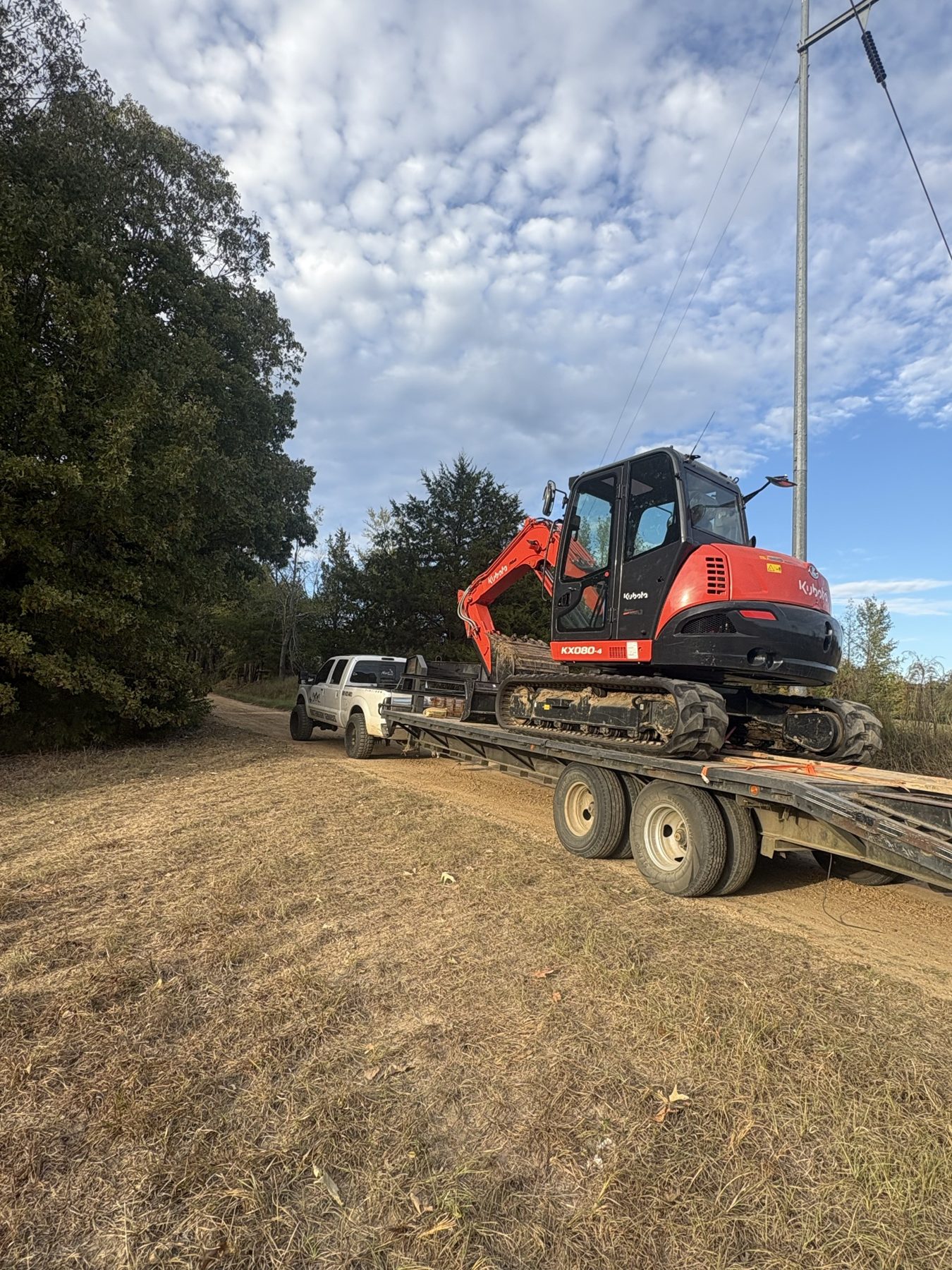 Excavator loaded on a trailer behind a pickup