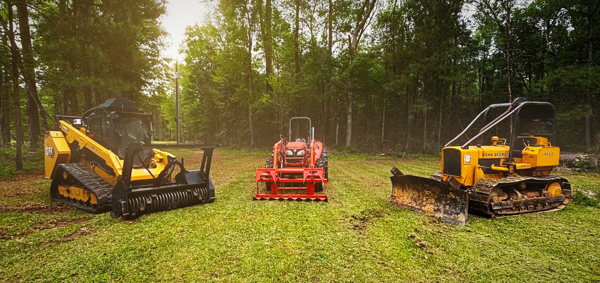 Track loader with mulching head, tractor and dozer lined up at the edge of a field